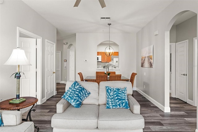 living room featuring ceiling fan with notable chandelier and dark hardwood / wood-style floors