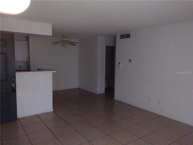 tiled empty room featuring ceiling fan