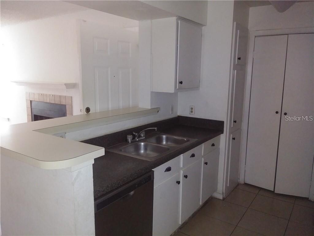 kitchen with light tile patterned floors, dishwasher, sink, white cabinetry, and kitchen peninsula