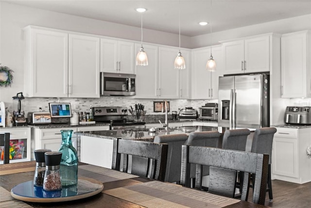 kitchen featuring decorative backsplash, dark hardwood / wood-style floors, white cabinetry, appliances with stainless steel finishes, and decorative light fixtures