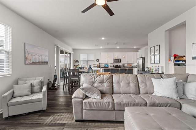 living room with ceiling fan and dark wood-type flooring