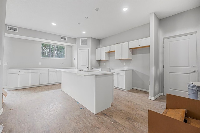 kitchen with a center island, white cabinets, and light hardwood / wood-style flooring