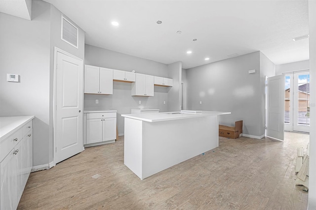 kitchen with white cabinetry, light hardwood / wood-style floors, and a center island