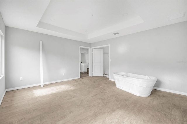 unfurnished bedroom featuring a tray ceiling and hardwood / wood-style flooring