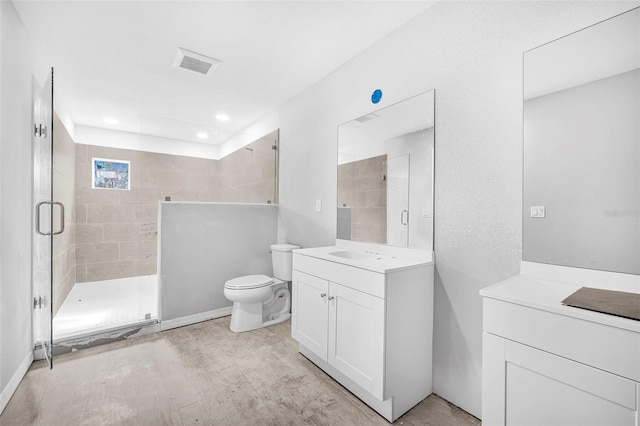 bathroom featuring wood-type flooring, toilet, an enclosed shower, and vanity