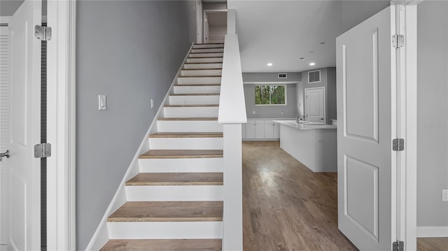 stairs with baseboards, wood finished floors, visible vents, and recessed lighting