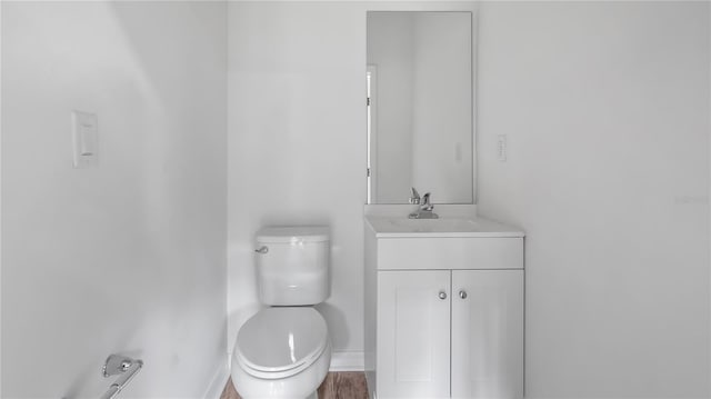 bathroom with toilet, baseboards, wood finished floors, and vanity