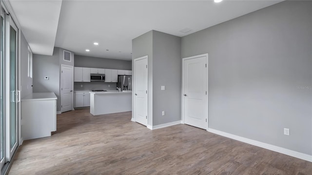 kitchen with stainless steel appliances, light wood-type flooring, light countertops, and white cabinetry