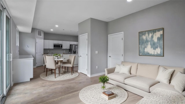 living room with baseboards, recessed lighting, visible vents, and light wood-style floors