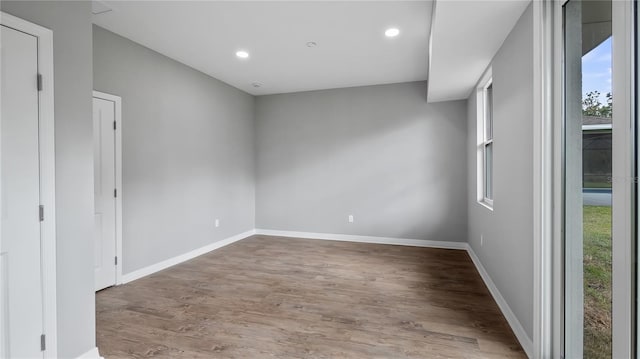 unfurnished room with recessed lighting, wood finished floors, and baseboards