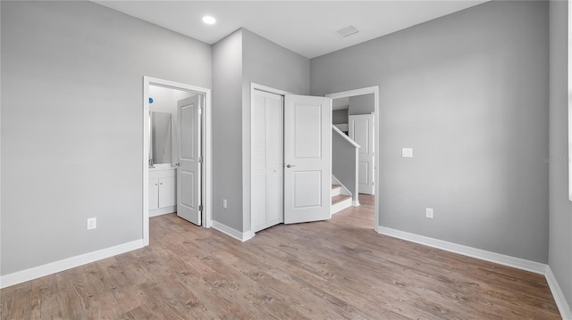 unfurnished bedroom featuring baseboards, wood finished floors, and ensuite bathroom