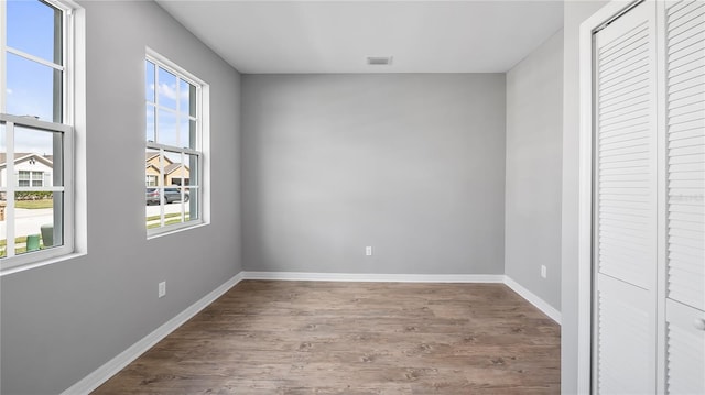 unfurnished bedroom featuring baseboards, a closet, visible vents, and wood finished floors