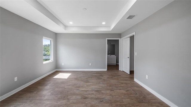 unfurnished room featuring visible vents, baseboards, dark wood finished floors, a raised ceiling, and recessed lighting