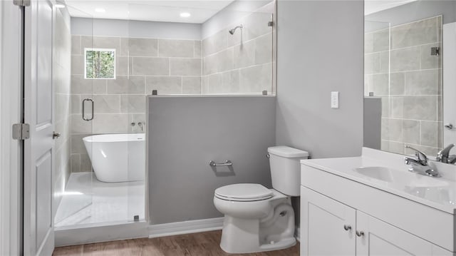 full bathroom with toilet, a shower with door, wood finished floors, a freestanding bath, and vanity