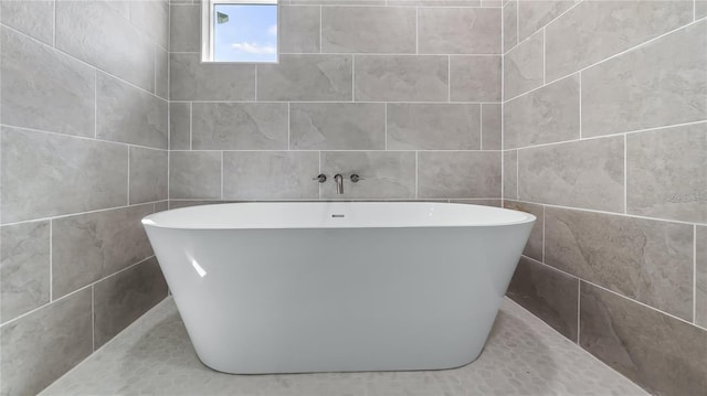 full bathroom with a freestanding bath and tile walls