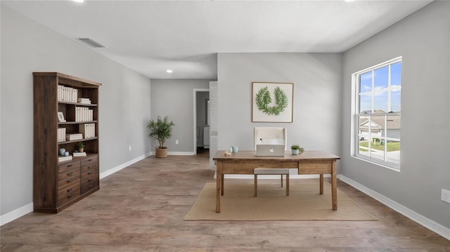 office space featuring baseboards, visible vents, and wood finished floors