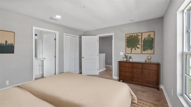 bedroom with visible vents, baseboards, ensuite bath, light wood-style floors, and a closet