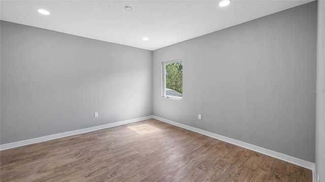 spare room with baseboards, wood finished floors, and recessed lighting