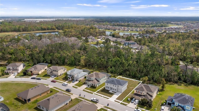 drone / aerial view featuring a water view, a residential view, and a view of trees