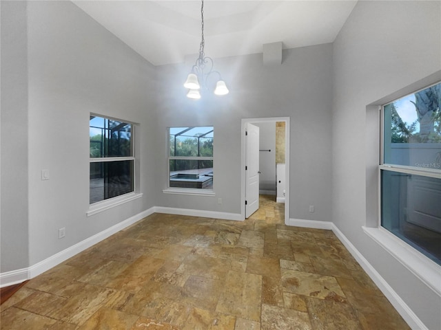 unfurnished dining area with a towering ceiling, tile patterned flooring, and an inviting chandelier