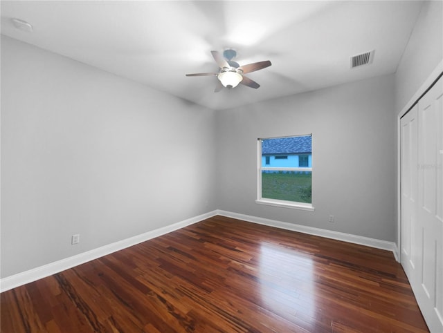 unfurnished bedroom featuring visible vents, a closet, baseboards, and dark wood-style flooring