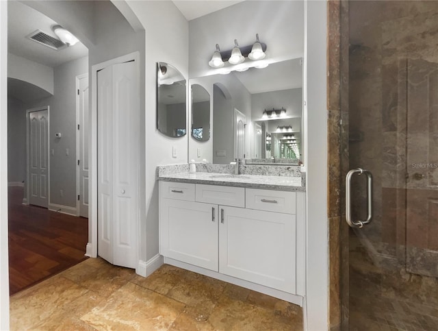 bathroom featuring a closet, visible vents, a stall shower, vanity, and baseboards