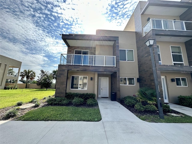 view of front of property with stucco siding, stone siding, and a front lawn