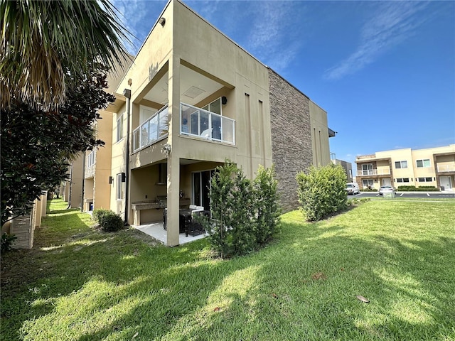 rear view of property featuring a yard and a balcony