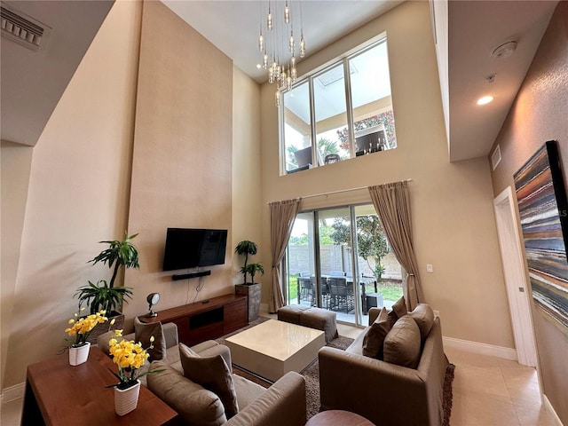 living area featuring visible vents, baseboards, a chandelier, a towering ceiling, and light tile patterned flooring