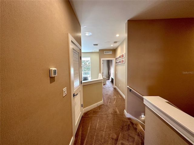 corridor featuring visible vents, baseboards, carpet, and an upstairs landing