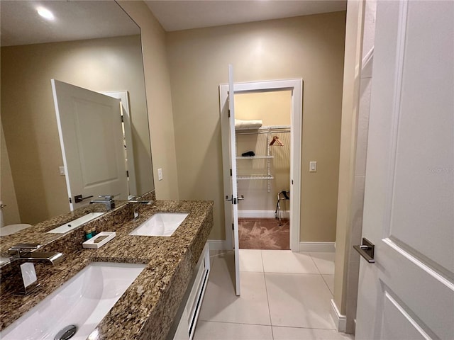 full bathroom with a sink, baseboards, double vanity, and tile patterned flooring