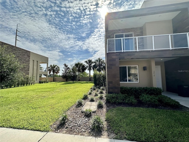 view of side of property with a balcony and a yard