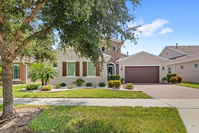 view of front of house with stucco siding, an attached garage, decorative driveway, and a front lawn