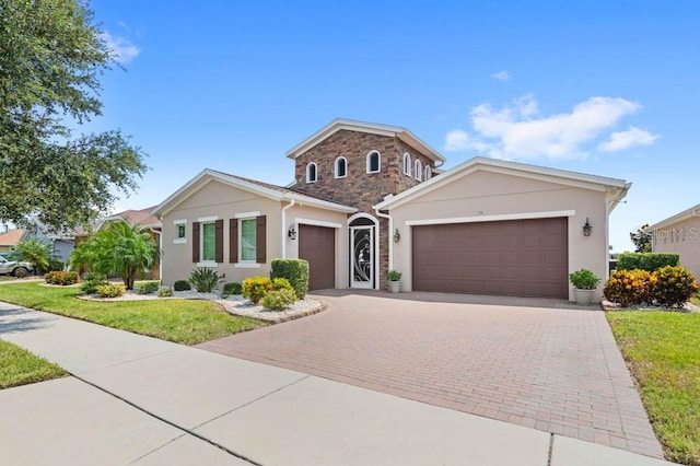 view of front facade featuring decorative driveway, a front lawn, an attached garage, and stucco siding