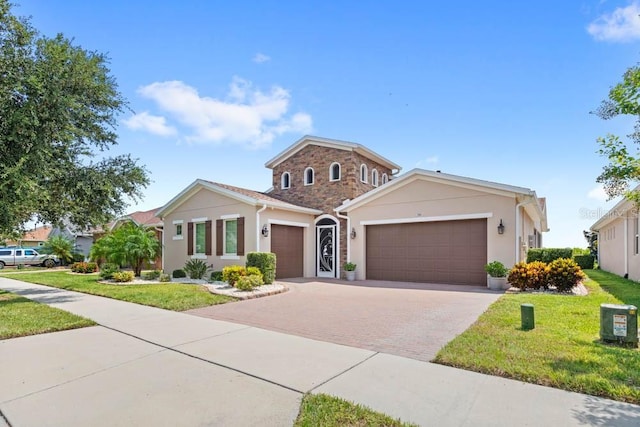 view of front facade with a garage, stucco siding, decorative driveway, and a front yard