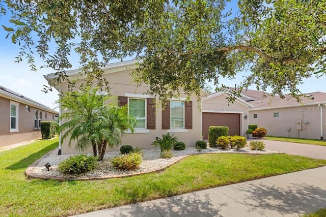 view of front of home featuring stucco siding, a front yard, a garage, and driveway