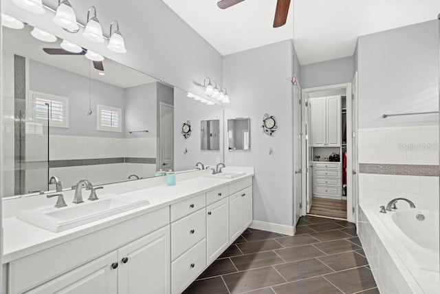 full bathroom with a sink, ceiling fan, double vanity, and a bath