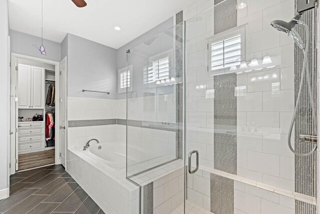 bathroom featuring a bath, a shower stall, a walk in closet, and ceiling fan