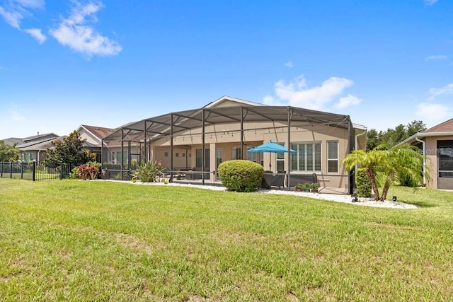 rear view of property with a lanai, a yard, and fence