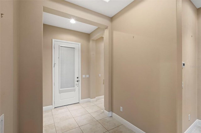 corridor with light tile patterned flooring and baseboards