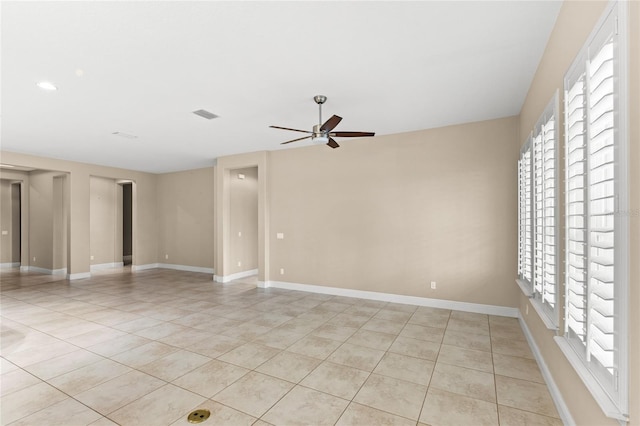 empty room with visible vents, light tile patterned floors, a ceiling fan, and baseboards