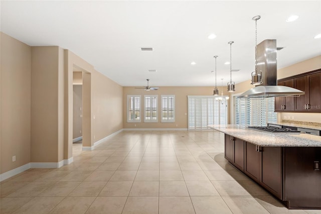 kitchen featuring visible vents, island exhaust hood, stainless steel gas stovetop, light tile patterned floors, and dark brown cabinets