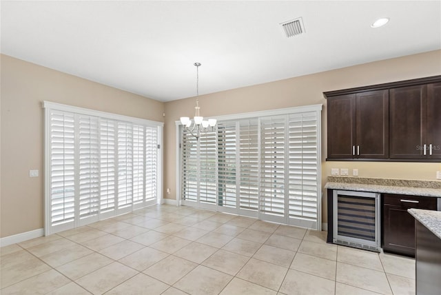 unfurnished dining area featuring light tile patterned floors, beverage cooler, baseboards, visible vents, and a chandelier