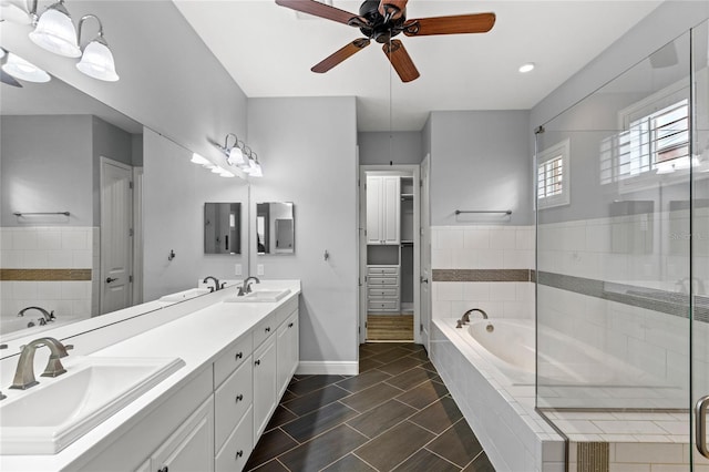 bathroom with a garden tub, double vanity, baseboards, and a sink