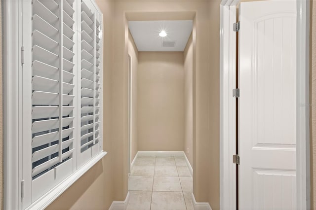 hallway featuring light tile patterned floors, visible vents, and baseboards