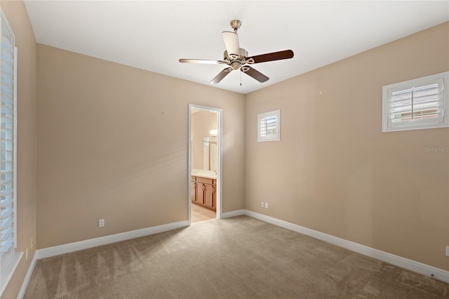 spare room featuring light colored carpet, baseboards, and ceiling fan