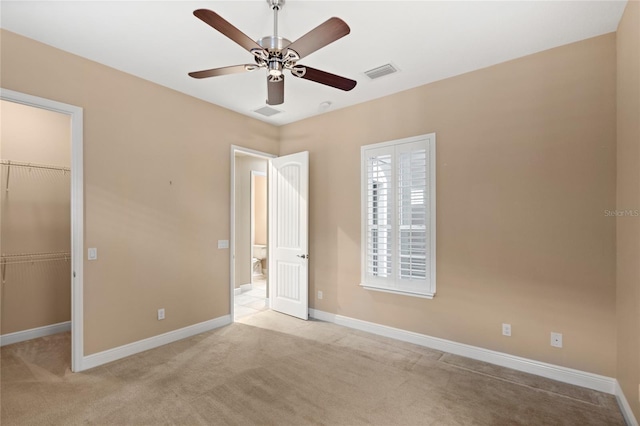 unfurnished bedroom featuring visible vents, light carpet, a closet, and a walk in closet