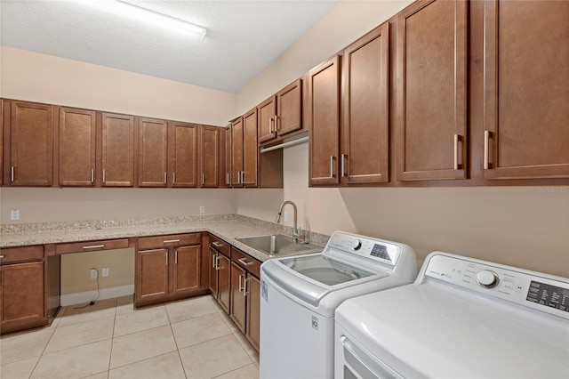 laundry area featuring light tile patterned floors, cabinet space, a sink, a textured ceiling, and washing machine and dryer