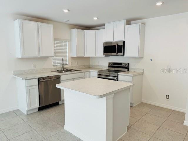 kitchen featuring appliances with stainless steel finishes, light tile patterned flooring, sink, a center island, and white cabinetry