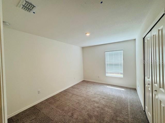 unfurnished bedroom featuring visible vents, carpet floors, and baseboards